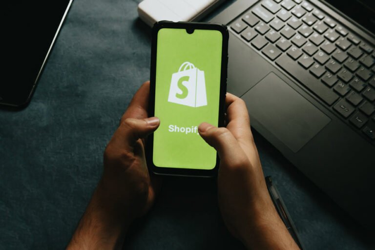 hands-holds-a-cell-phone-showing-the-shopify-logo